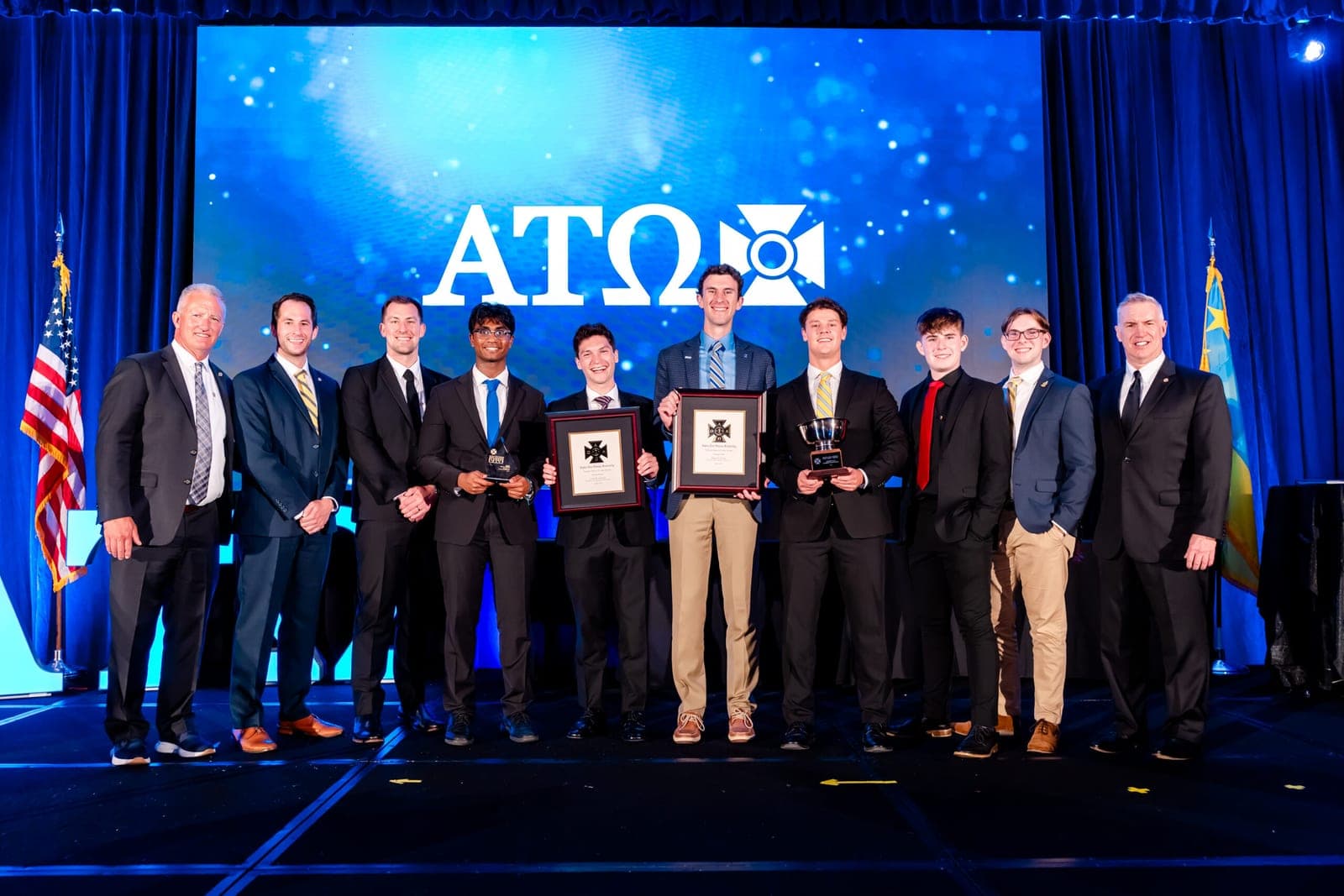 ATO brothers stand on stage with awards