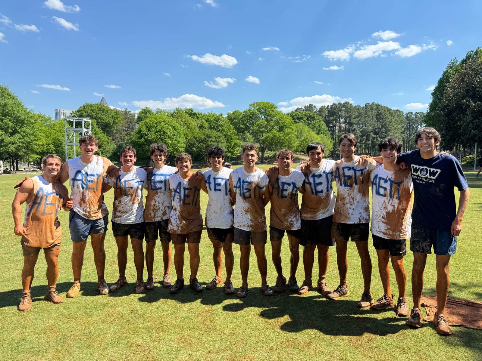 AEPi brothers pose in muddied clothes after a sporting event